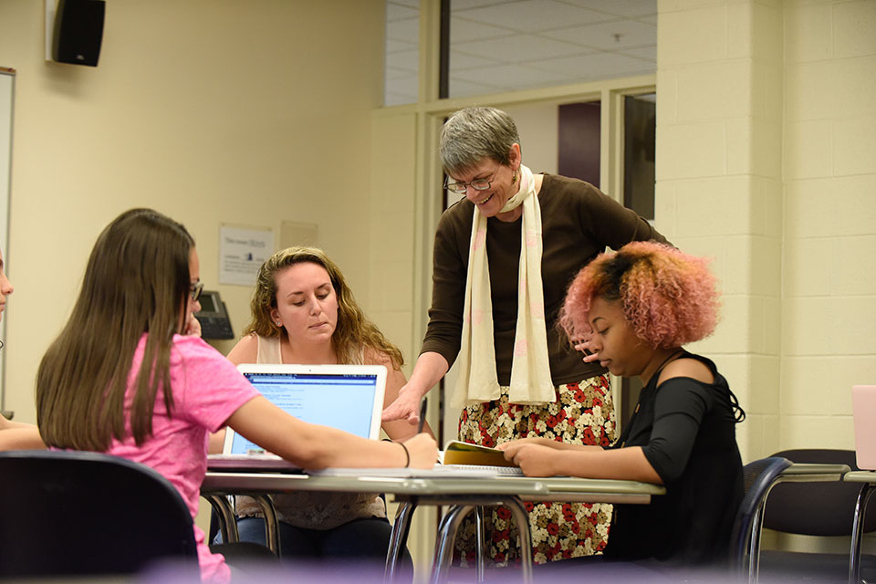 A faculty member works with students in the classroom.