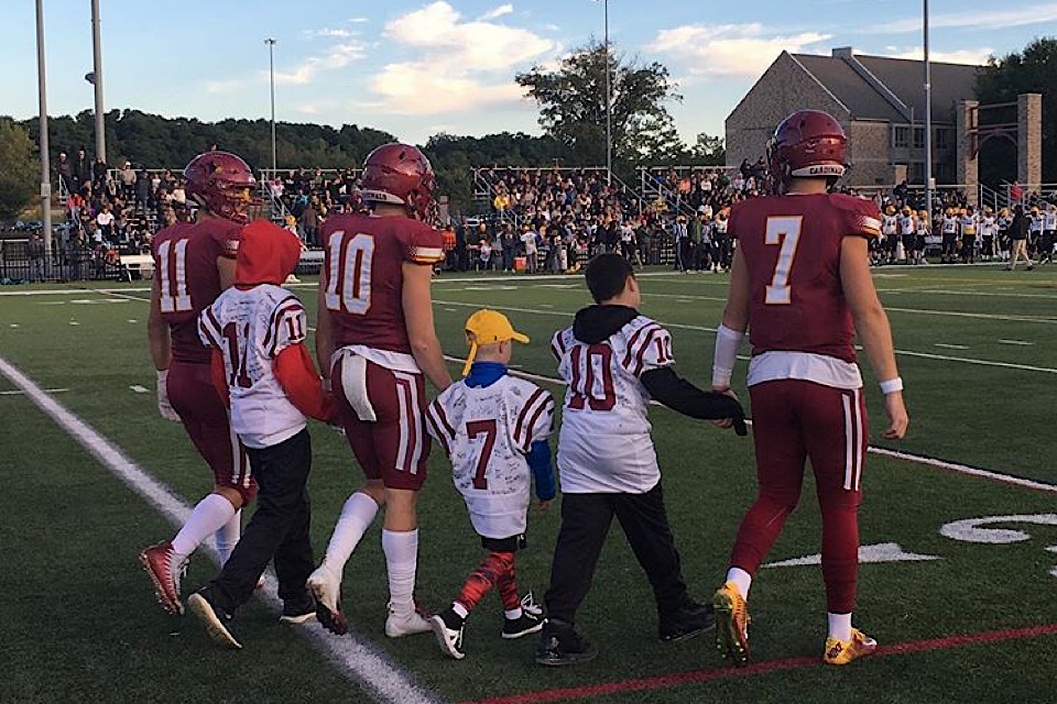 Cardinal football players and honorary coaches take the field during the Courage Bowl.