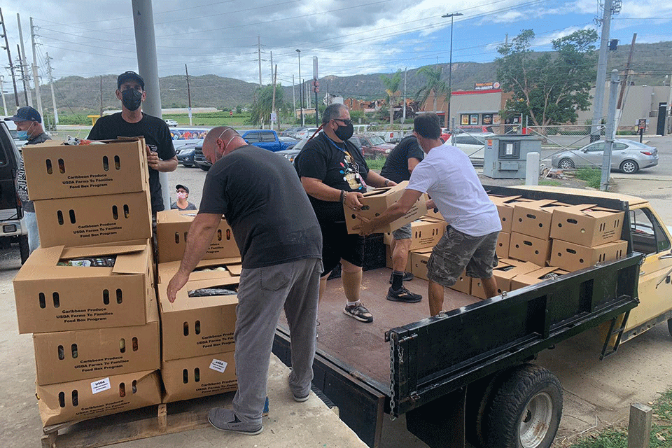 Residents of Puerto Rico unload food boxes, thanks to a collaboration between Puerto Rico Rise Up and Caribbean Produce. Fisher Professor Dr. Kermin J. Martínez-Hernández helped organize the effort.  