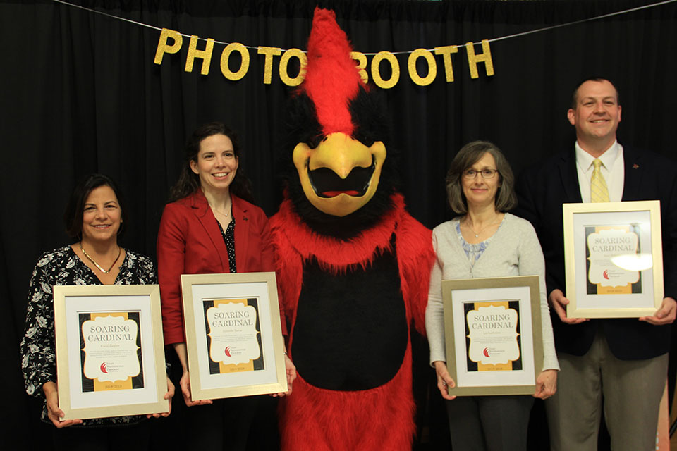 Carol Ziegler, Amanda Burns, Liz LaChance, and Dave Roberts-all winners of the 2019 Soaring Cardinal Award-pose with The Cardinal mascot.