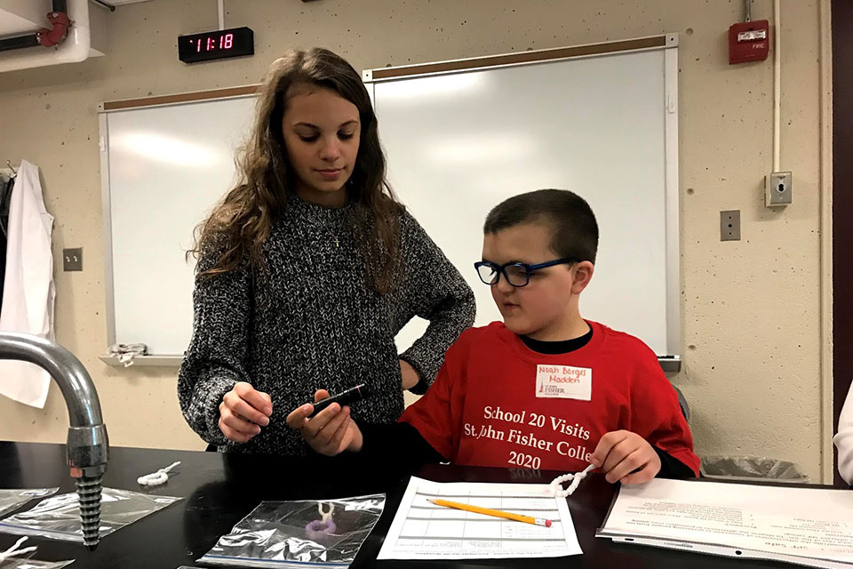 A student from Dr. Tweet's class works with a fourth grade student from School No. 20.