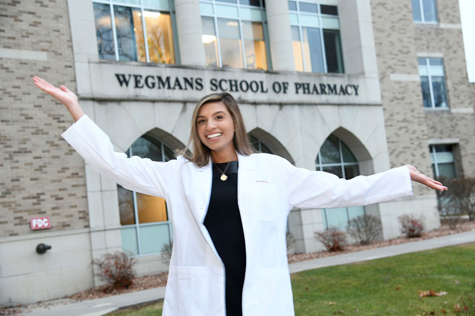 A pharmacy student poses in her white coat.