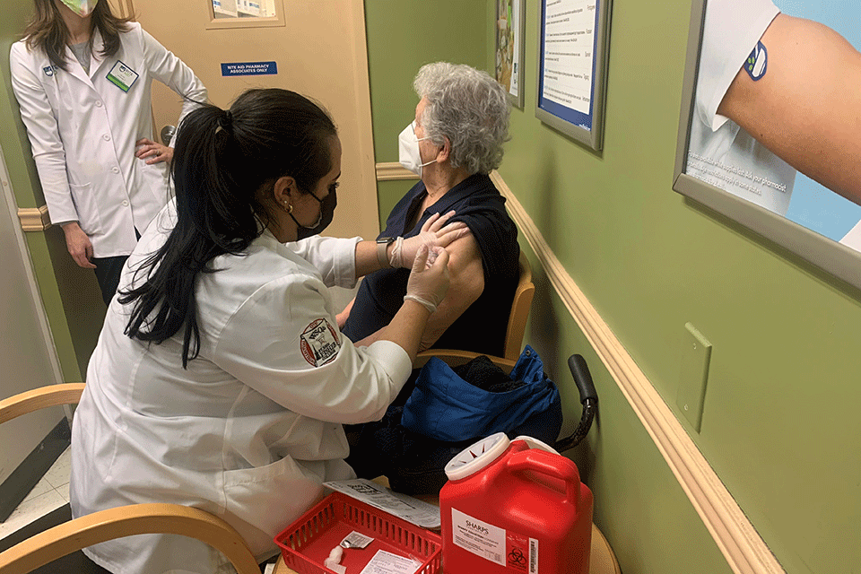 Pharmacy student Christiana Santos administers a COVID-19 vaccine.