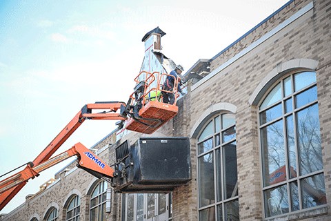 A member of the construction crew works on the brick exterior of Lavery Library.