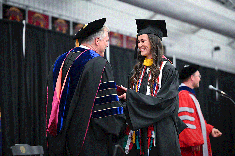 School of Business graduate Angelea Collins accepts her diploma from Dean Dan Connolley.