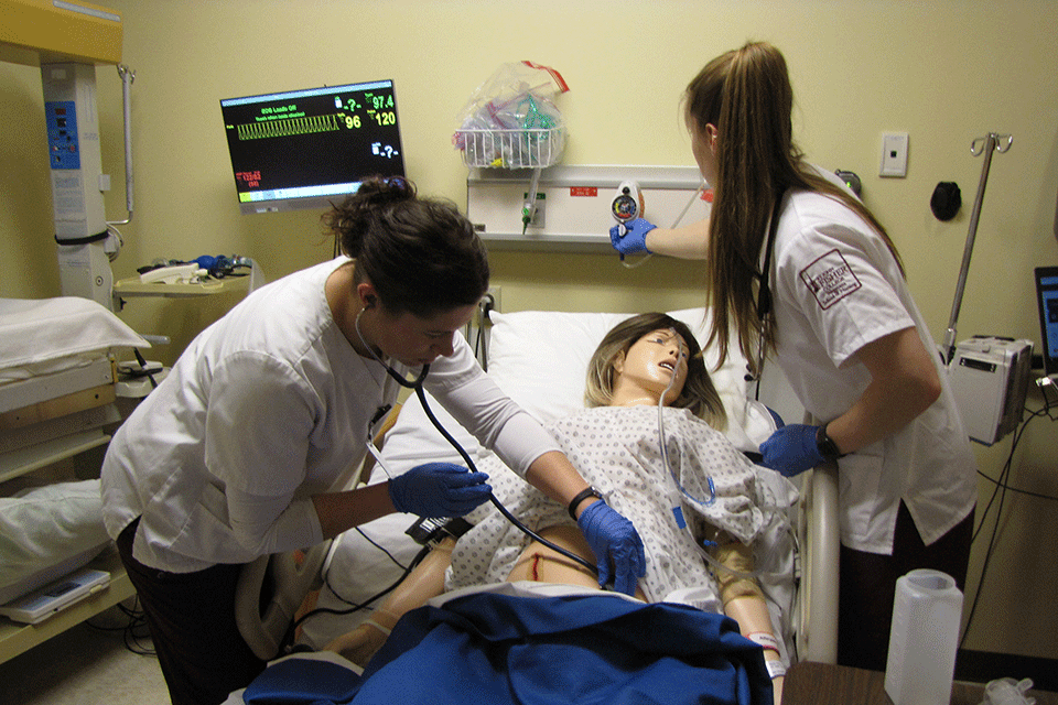 Two students in the Wegmans School of Nursing test their knowledge in the SIM Center.