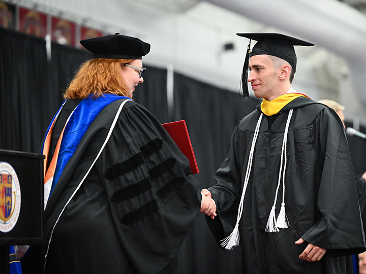 A graduating senior receives his diploma at commencement.