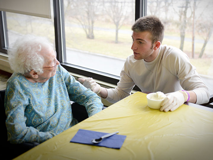 A pharmacy student serves up ice cream and conversation for a resident of Episcopal Senior Life.