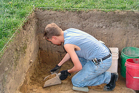 Student digging at archaeological field site.