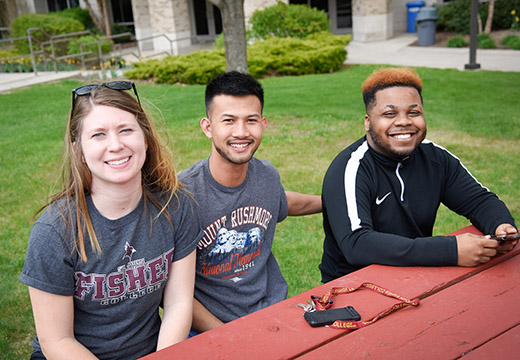 Three Fisher students sit at a picnic table.